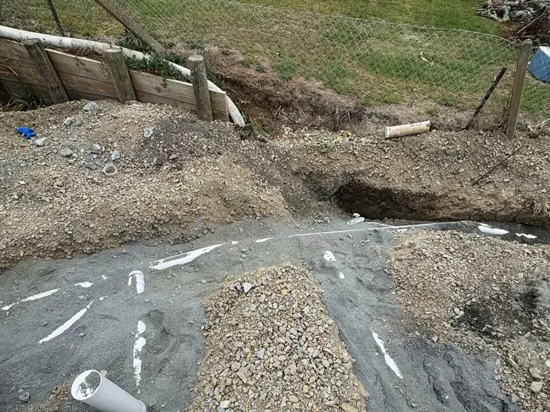 Excavation site with new PVC drainage pipes laid in gravel bedding